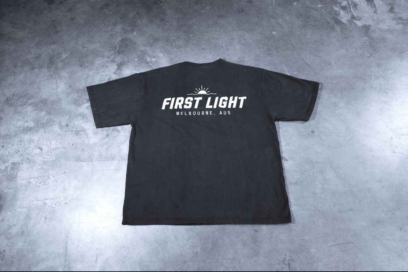 Back flat lay of the Dawn heavyweight tee showing the embroidered FIRST LIGHT Melbourne back graphic